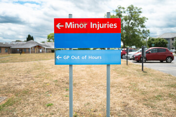Typical Minor Injury sign seen together with an out of hours GP department at a typical NHS hospital in Britain. A patient car park is in the right, administration buildings in the distance.