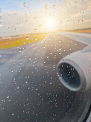 A plane is on the runway with raindrops on the window