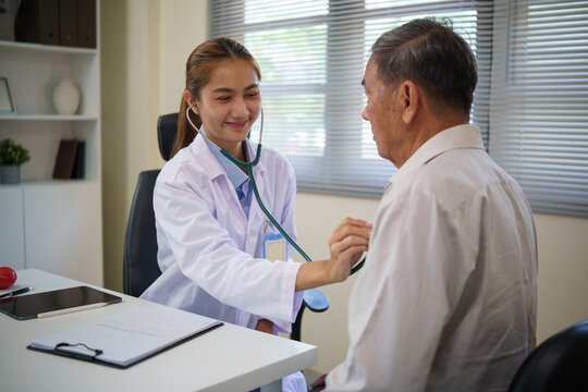 Female doctor using a stethoscope to examine the heart of a senior male patient in a clinic. Health care concept.