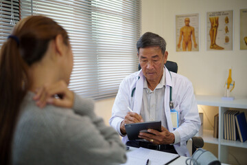 Patient experiencing neck pain consulting with a male doctor in a clinic. Health care concept.