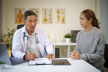 Obraz premium Senior male doctor explaining medical information to a young female patient during consultation.