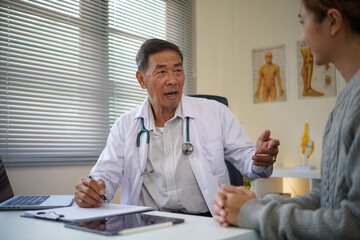 Senior male doctor explaining medical information to a young female patient during consultation.
