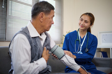 Female nurse measuring blood pressure of an elderly man during a home healthcare visit.