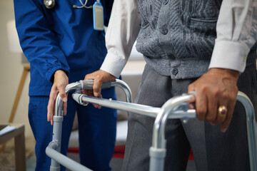 Close up of elderly man using a walker with support from a home care nurse.