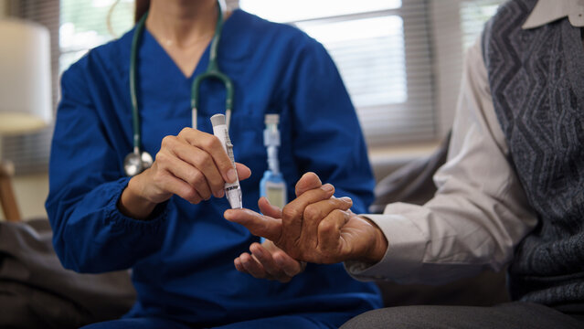 Home caregiver  using lancet to check blood sugar levels of older patient.  Health care concept.