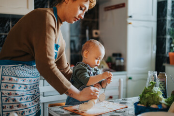 A caring mother assists her young child while baking in their cozy kitchen, fostering family...