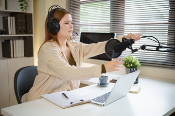 Podcaster in headphones adjusting professional microphone, ready to record in modern workspace.