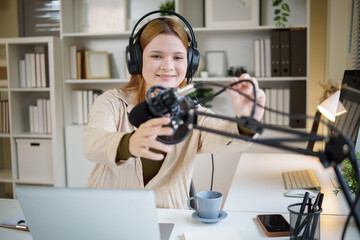 Female podcaster setting up microphone for audio recording in home studio.
