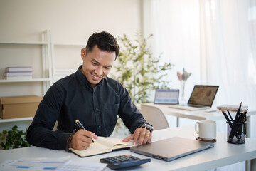 Happy businessman planning and analyzing data in a modern workplace.