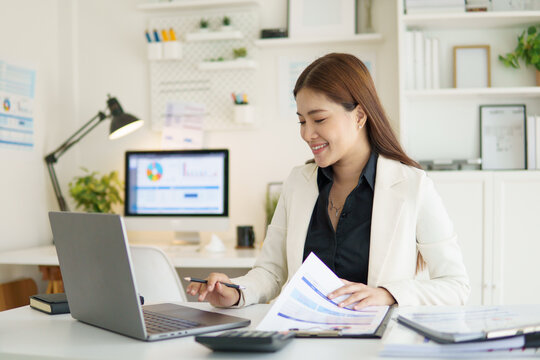 Confident female accountant reviewing charts and graphs in a bright modern office.