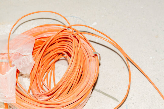 A coil of electrical cable in orange winding.
