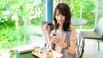カフェでスマートフォンを使う笑顔の女性
