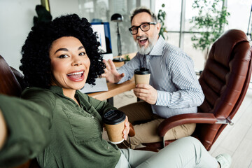 Cheerful colleagues enjoying coffee while collaborating in a stylish office setting showcasing...
