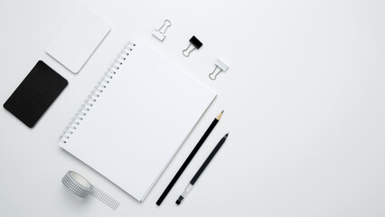 Naklejka premium Monochrome stationery items arranged neatly. On a white background, an empty mock up notebook, white and black cards