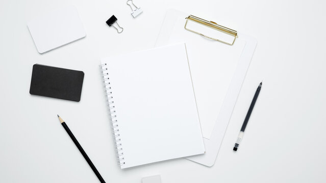 Monochrome stationery items. On a white background, an empty mock up notebook and clipboard, white and black cards