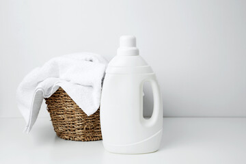 Laundry detergent branding mock up and basket filled with clean white towels. Household cleaning...