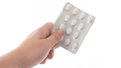 Hand holding a blister pack of white tablets against a plain background with a focus on health and...