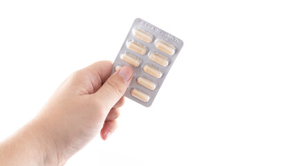 Hand holding a blister pack of capsules against a plain white background showcasing medication for...