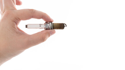 Hand holding a spark plug against a plain background for automotive maintenance demonstration