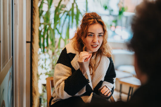 A young woman engaged in a friendly talk inside a warm and inviting cafe space.
