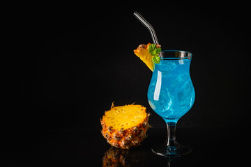 Boozy Blue Hawaii Cocktail with Rum and Pineapple on black background