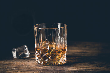 Whiskey with ice in glasses and bottle, dark background, copy space