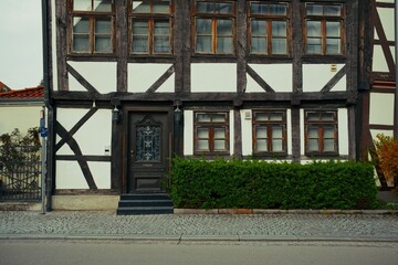 Close-up view of a traditional half-timbered house facade with dark wood beams, white plaster, and vintage windows in Wolfenb&uuml;ttel, Germany.