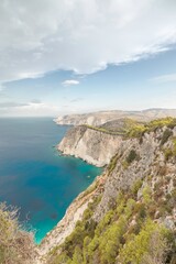 Majestic cliffs rise sharply above the shimmering turquoise waters, framed by lush greenery. The...
