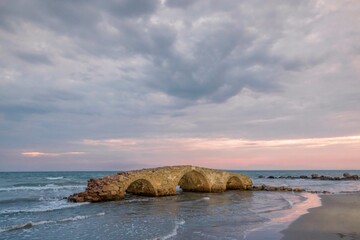 As the sun dips below the horizon, colors blaze across the sky, casting a warm glow on the ancient...