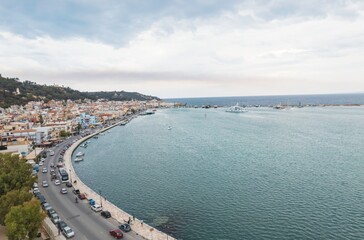 From above, a picturesque seaside town unfolds along the curving shoreline with vibrant buildings...