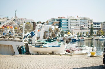 Fishermen's boats are docked in a vibrant harbor, surrounded by modern buildings under clear blue...