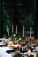 Elegant Dinner Table Set with Candle Holders, Fine Dishes, and Greenery for a Sophisticated Dining Experience