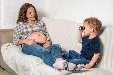 Curious son looking closely with binoculars at his mom’s pregnancy
An infant wants to know what...