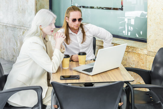 Ginger man and albino woman meeting at cafe with laptop and coffee - Powered by Adobe