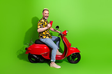 Charismatic mature man with funky blond hair on a red scooter showing a phone, set against a...