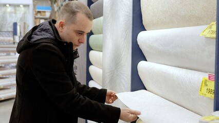 Customer selecting wallpaper samples, comparing patterns and textures while planning home interior...
