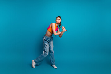 Young woman in casual outfit posing playfully against a vibrant blue background, exuding charm and a stylish summer vibe