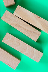 Light-colored wooden blocks, arranged chaotically on a bright green background, create a dynamic...