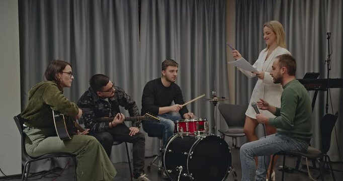 Music band practices before a concert. A female band manager guides musicians during rehearsal.