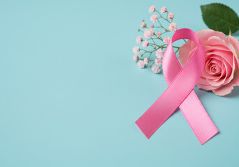 Pink ribbon with rose and baby's breath on a light blue background for breast cancer awareness theme