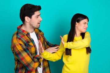 Young couple in casual wear expressing contrasting emotions on a vibrant teal background