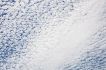 Fluffy clouds create a textured sky over a tranquil landscape during the late afternoon hours