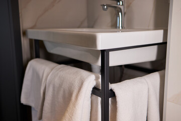 Elegant White Towels Neatly Displayed on a Stylish Modern Rack for a Sophisticated Touch