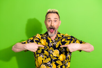 Charismatic man in a vibrant lemon-printed shirt expressing joy against a bright green background,...