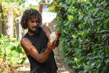 Strong Afro-Caribbean man cracking coconut with machete outdoors