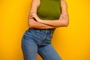 Stylish woman in green top and denim posing confidently against bright yellow background exuding...