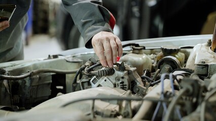 Professional mechanic checking engine parts, performing diagnostics and maintenance on a vehicle in...