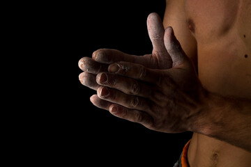 Close-up of a shirtless muscular man rubbing chalk on his hands before training or climbing. The...