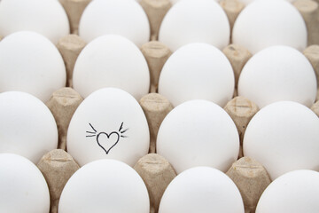 white chicken eggs in the cardboard egg tray with a drawing of heart