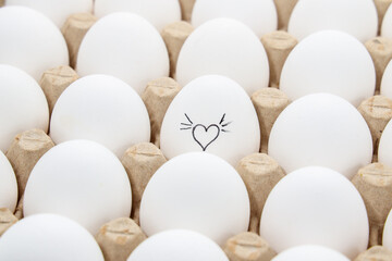 white chicken eggs in the cardboard egg tray with a drawing of heart